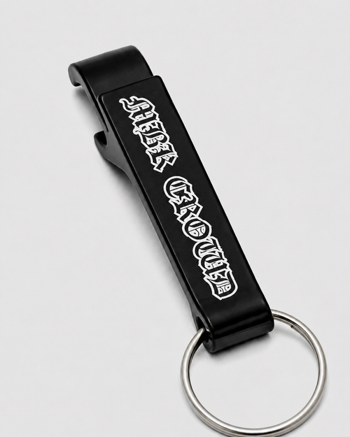 MBK Opener de perto: abridor de metal preto com MBK Crowd em letra gótica branca e argola de chaveiro